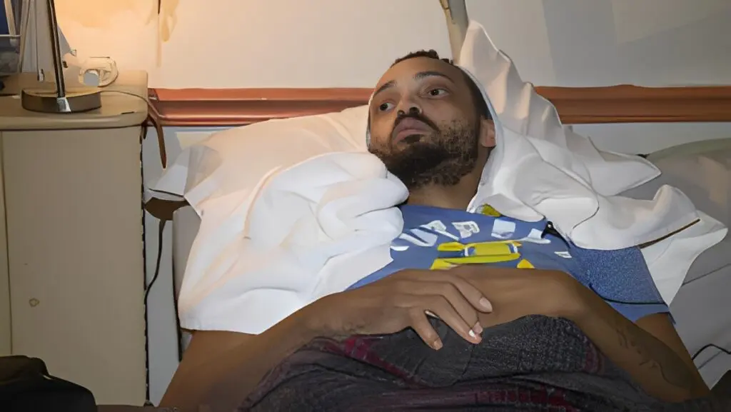 Man resting in hospital bed, looking thoughtful.