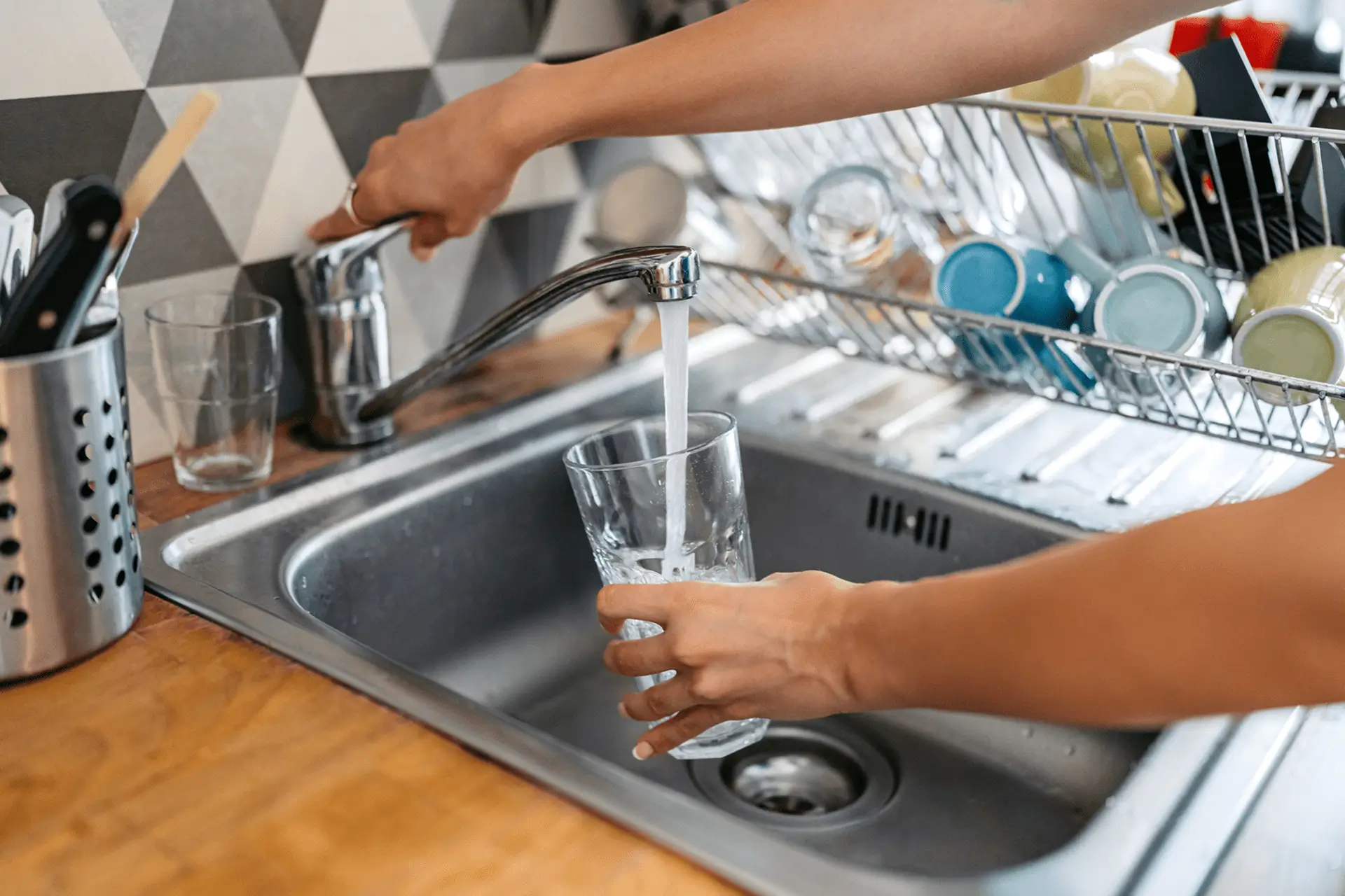 Hands filling glass with tap water at sink